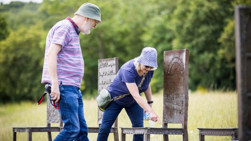 A lady taking a closer look one of the twelve chairs that form part of The Jurors art installation at Runnymede.